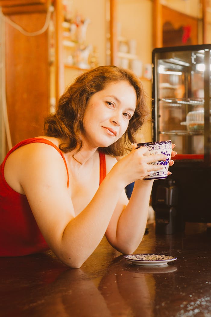 Relaxed woman savoring a hot drink in a warm, cozy kitchen setting.