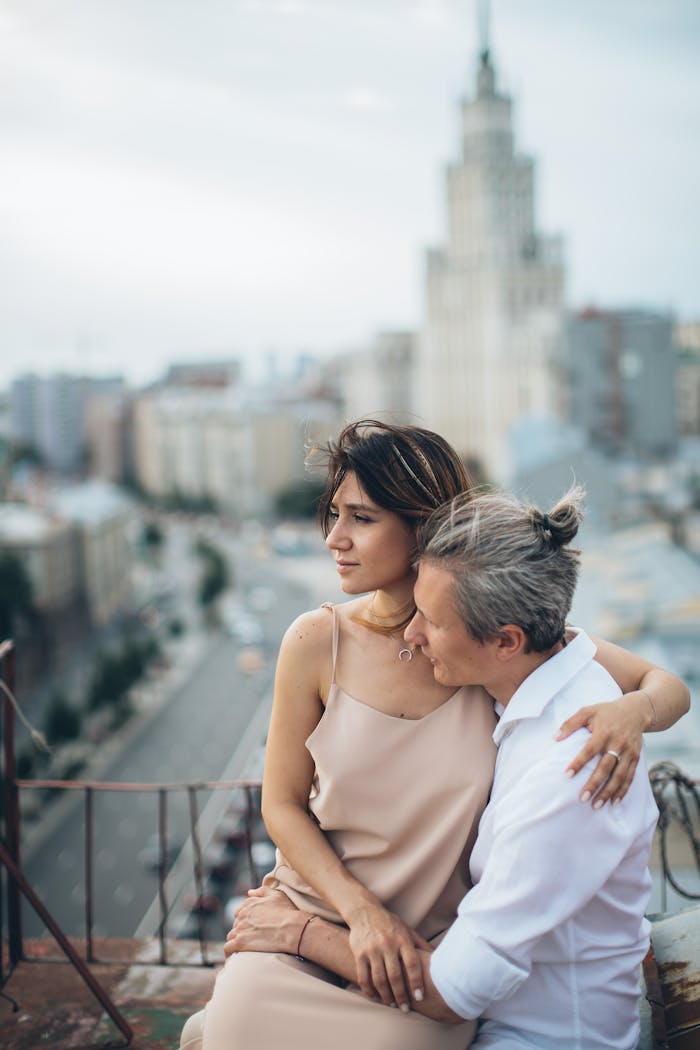 A romantic couple embraces on a rooftop, overlooking a city skyline, evoking love and togetherness.